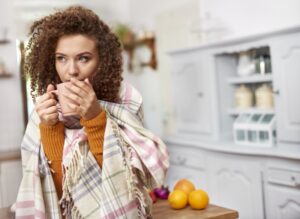 woman-huddled-with-blanket-drinking-out-of-mug