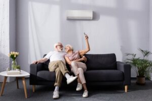senior-couple-on-couch-changing-temperature-of-mini-split-with-remote-control