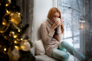 Heating_Young_woman_sitting_by_the_window_drinking_hot_coffee_Comfortable_Home_Interior_Women_Heat_temperature_Sweater_